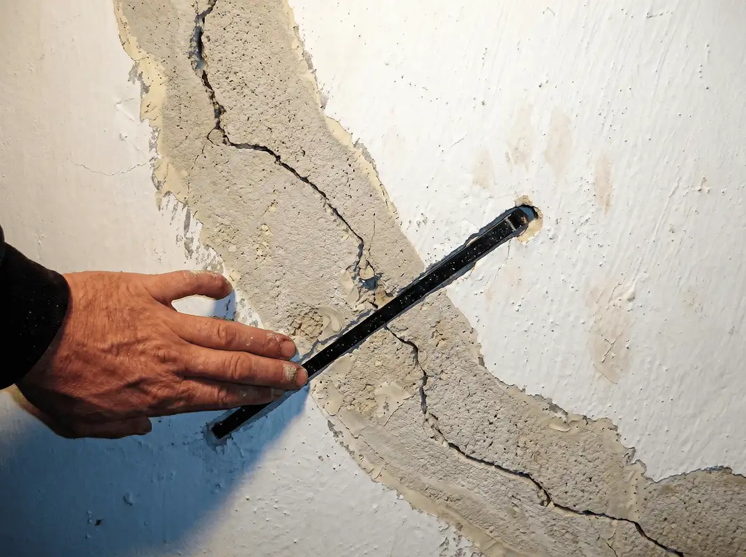 A wall with a large crack is being inspected by a professional in Orlando, FL