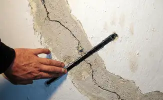 A wall with a large crack is being inspected by a professional in Orlando, FL